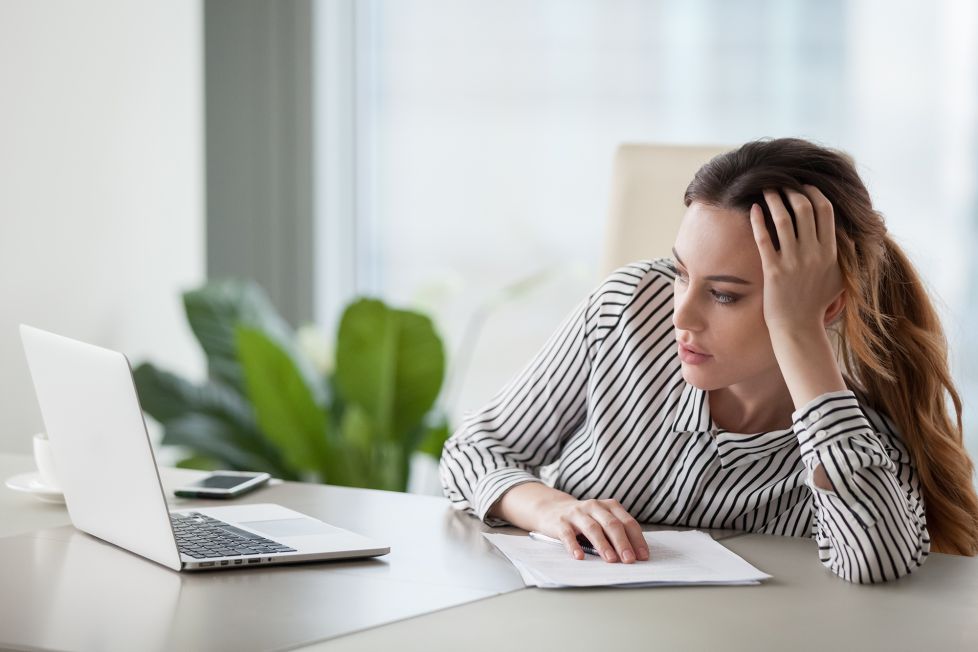 Imagem de uma mulher em frente a um computador com cara de cansada. Imagem ilustrativa de texto franquias baratas serviços 2021.
