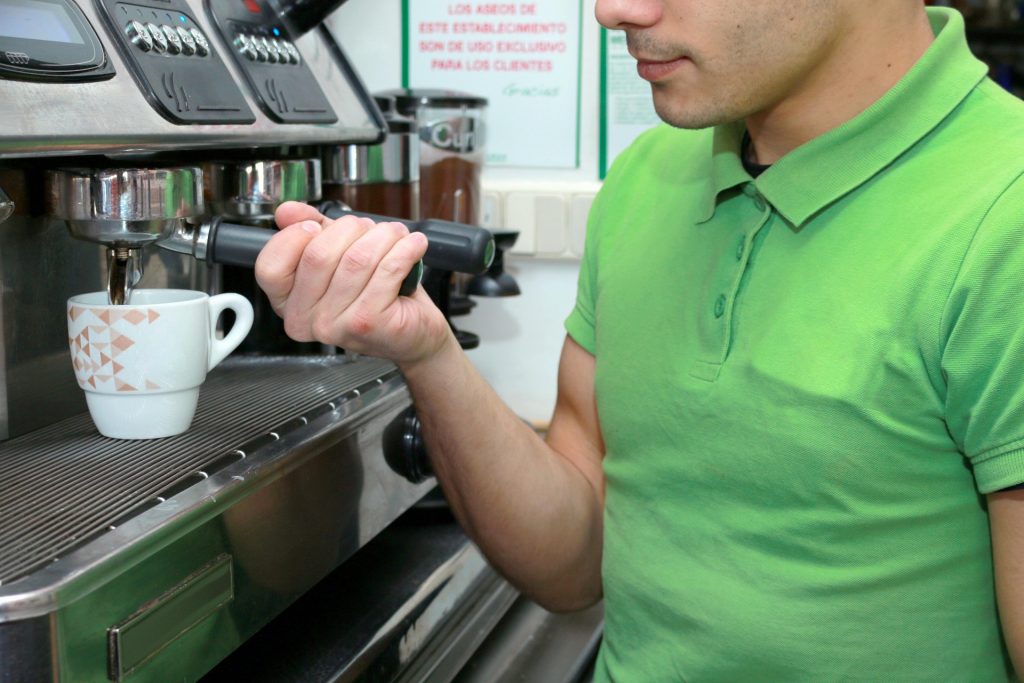 Homem servindo café em um cafeteria.  Ilustração do texto sobre vantagens microfranquia.