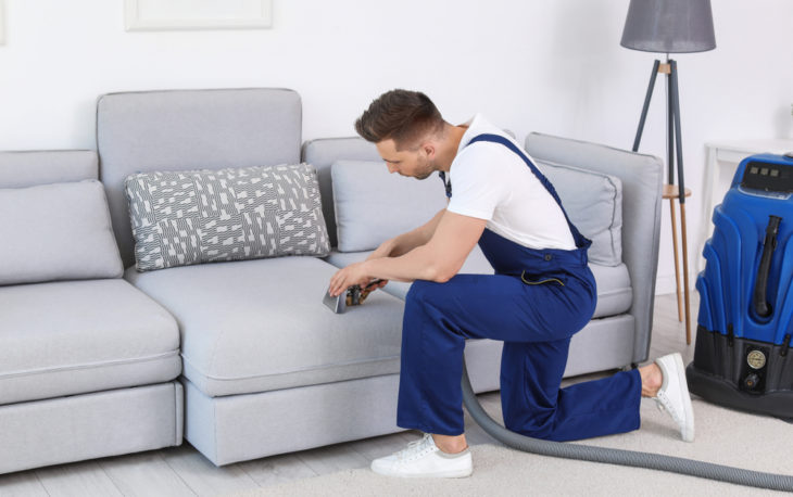 Franquia de lavagem a seco de estofados: homem fazendo a limpeza de um sofá