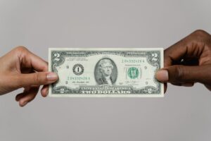Pessoas segurando nota de dólar na cor verde. Ilustração do texto sobre franquia financeira barata.