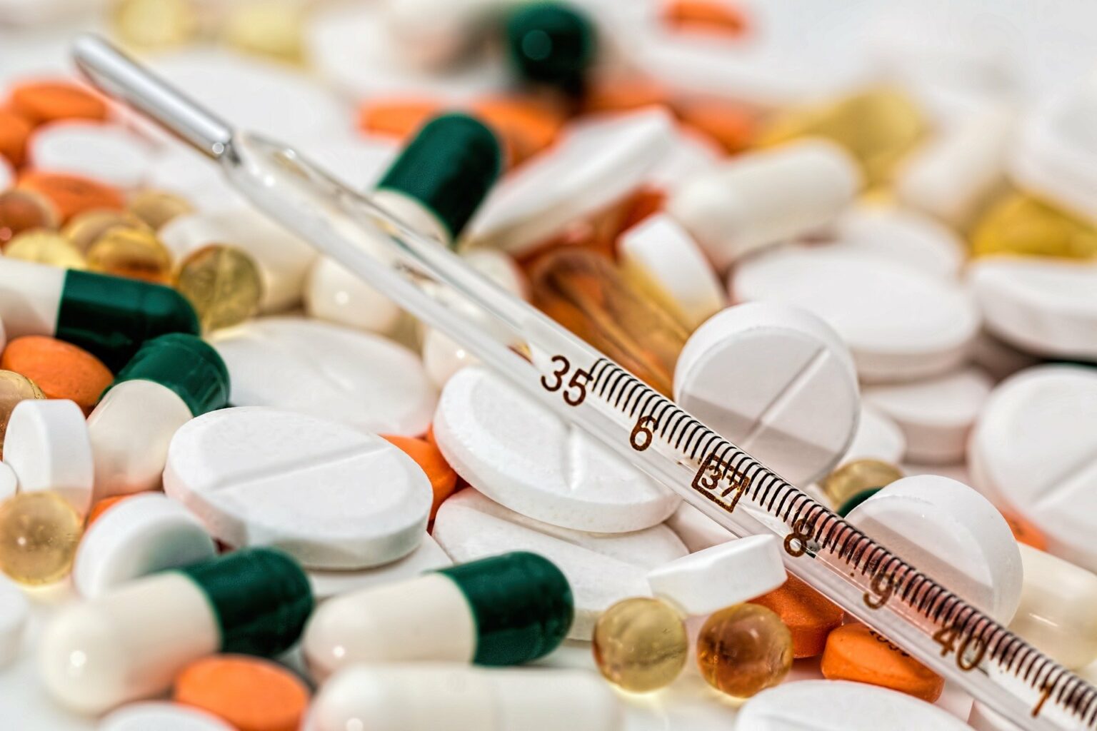 Vemos vários comprimidos de remédios e uma seringa (imagem ilustrativa).