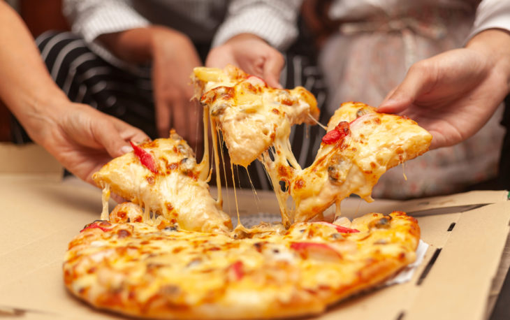 franquia de pizzas pré-assadas: amigos dividnindo uma pizza de marguerita