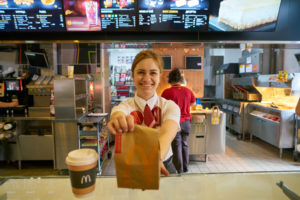Franquias McDonald's: funcionária do McDonalds fazendo entrega de um pedido no restaurante