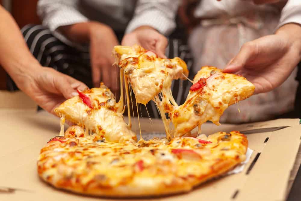 Negócios em alta: amigos pegando pedaço de pizza durante uma reunião