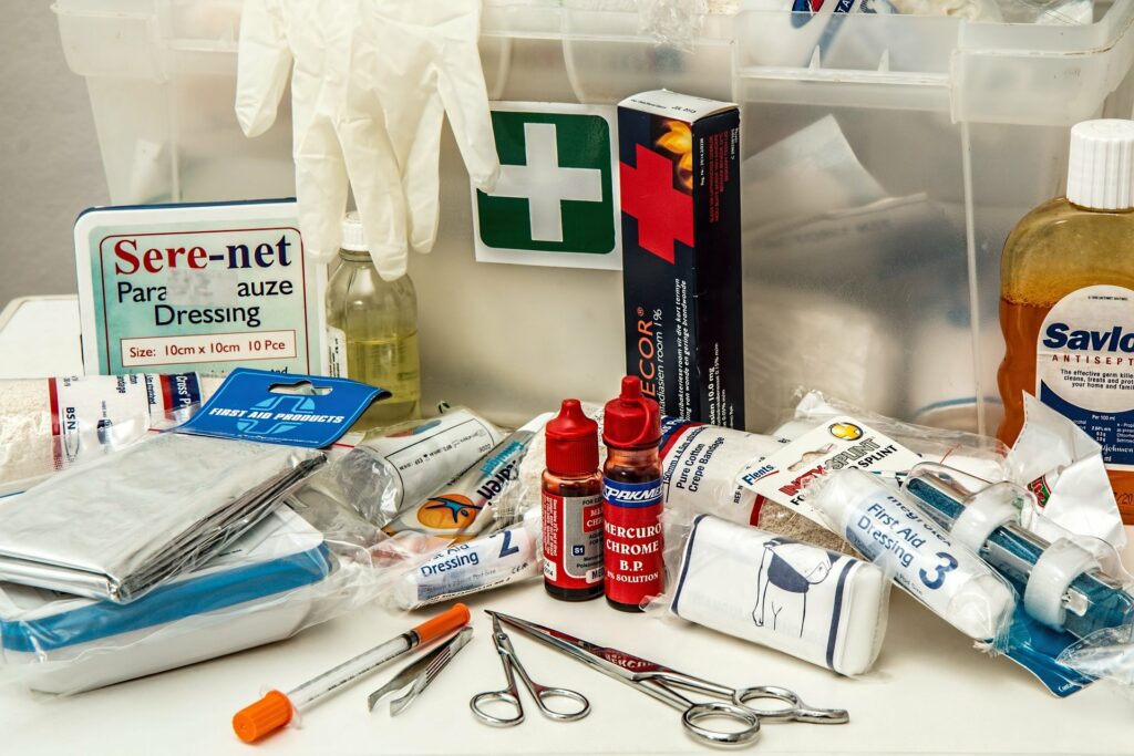 Vemos uma mesa cheia de produtos para tratamentos como gaze, curativos, luvas remédios, tesouras e mais (imagem ilustrativa). Texto: franquia de farmácia.