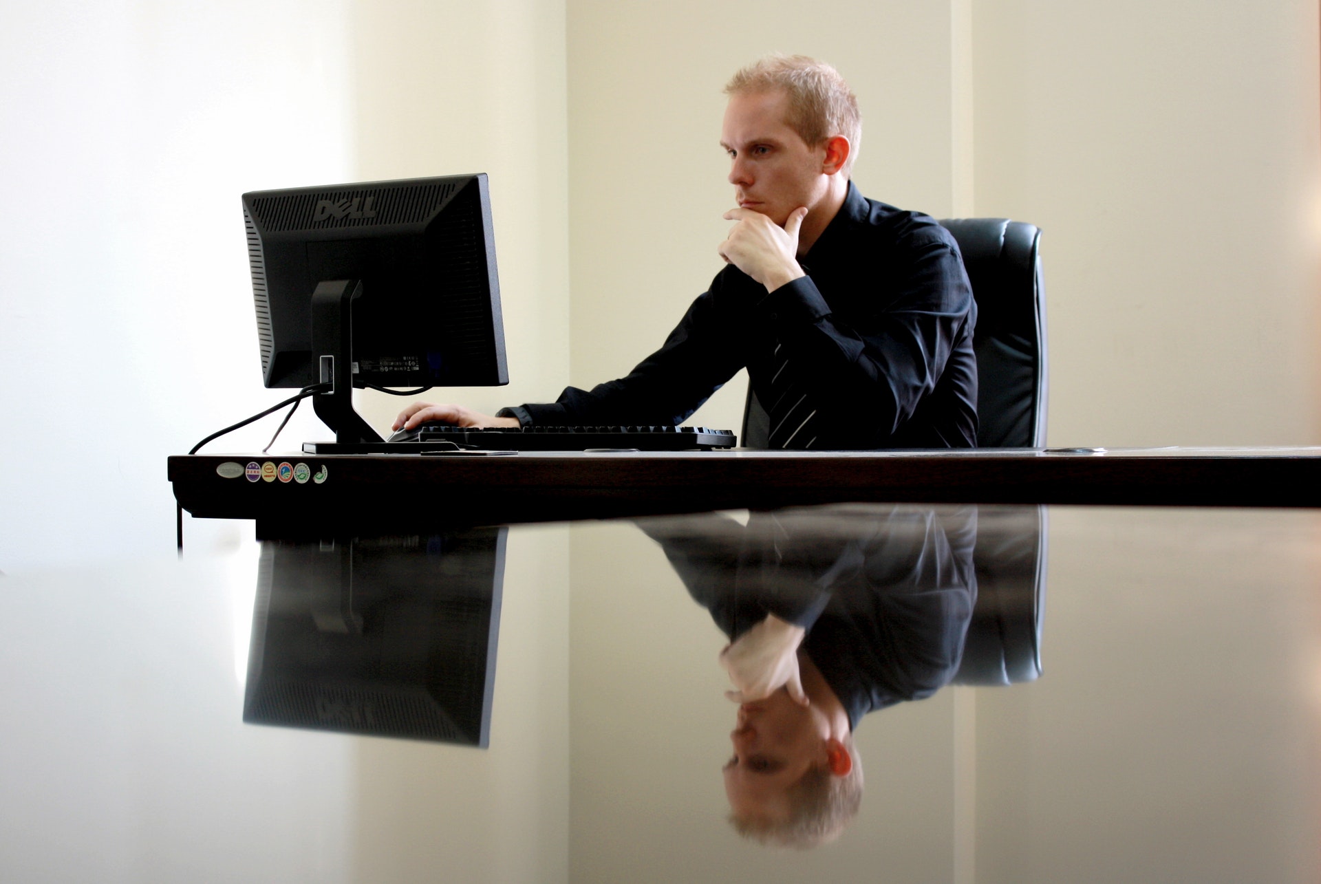 Homem de terno sentado em frente a um computador com olhar pensativo. Ilustração do texto sobre mercados para empreender.