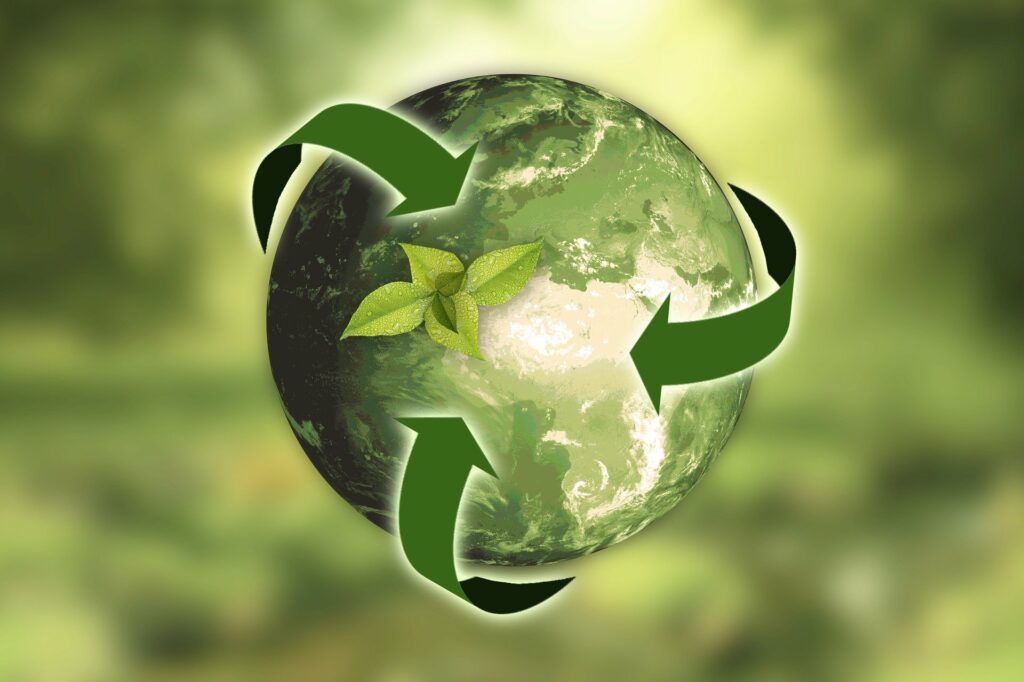 Foto de um globo verde, com as três setas da reciclagem também verde e um fundo verde desfocado (imagem ilustrativa). Texto: empreendedorismo verde.