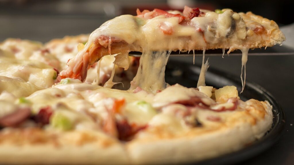 Foto de uma espátula retirando um pedaço de pizza em uma tábua. Imagem ilustrativa para texto franquia pizza Hut.
