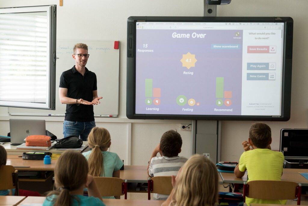 Professor em frente a vários alunos mostrando conteúdo em uma lousa digital. Imagem ilustrativa de texto como abrir o próprio negócio.