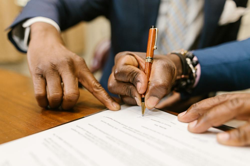 Mãos assinando papel com caneta marrom. Ilustração do texto sobre contrato de franquia.