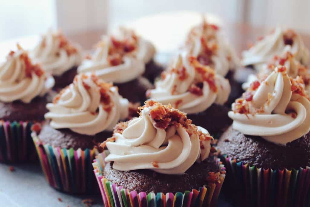 Imagem de cupcakes com coberturas brancas.