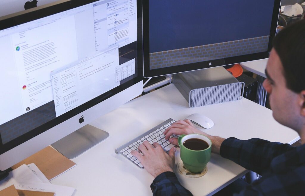 Vemos um homem de blusa azul sentado à mesa enquanto utiliza um computador (imagem ilustrativa). Texto: franchising e licenciamento.