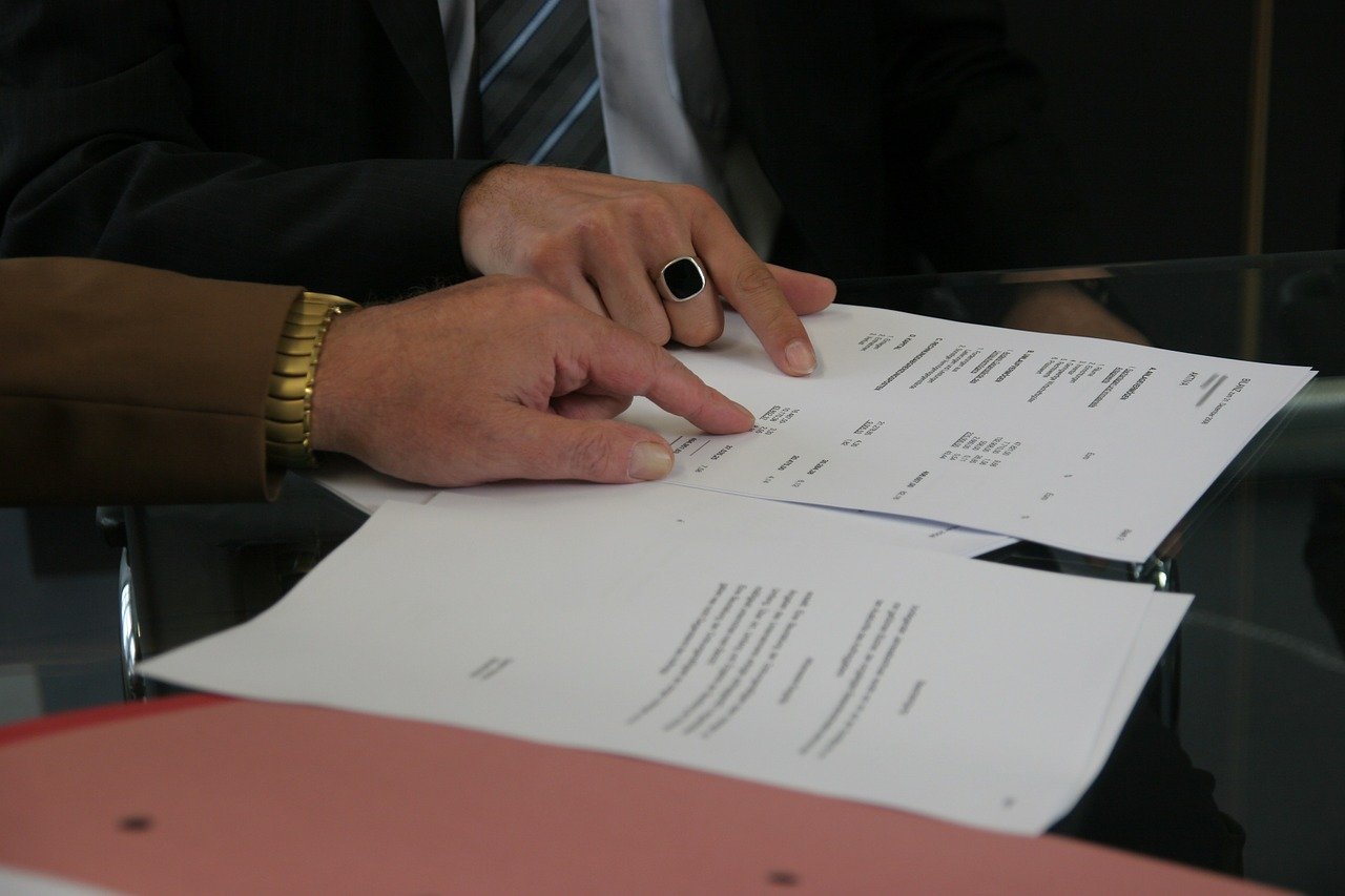 Vemos duas pessoas apontando seus indicadores para um contrato que está sobre a mesa (imagem ilustrativa). Texto: franquias com maior rentabilidade.