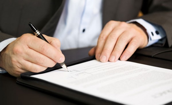 Imagem de um homem assinando um contrato (imagem ilustrativa). Texto: ideias para ganhar dinheiro.