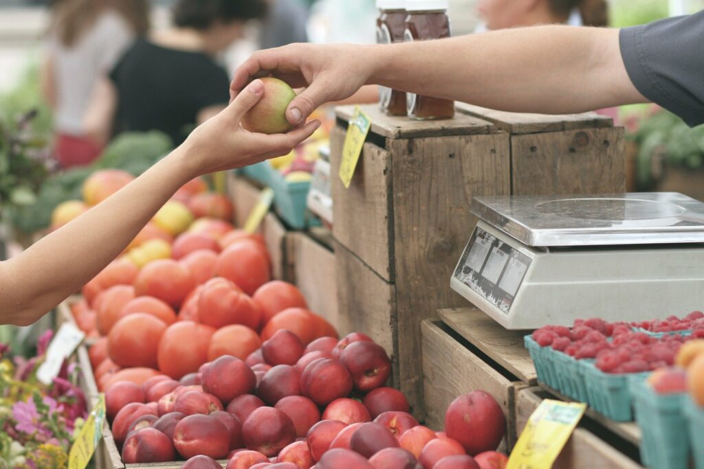 Imagem de uma pessoa comprando uma fruta em uma barraca (imagem ilustrativa). Texto: investimento em franquias.