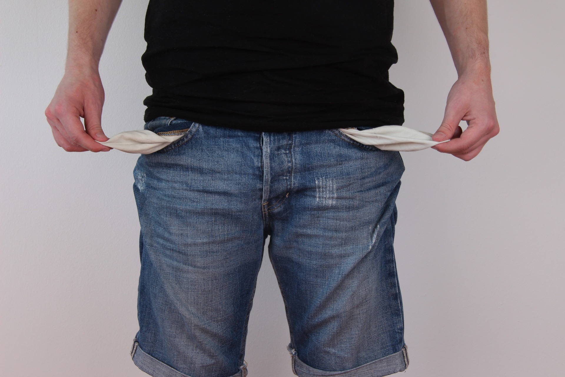 homem de blusa preta e short jeans mostrando como está sem dinheiro. imagem ilustrativa para texto montar negócio com pouco dinheiro.