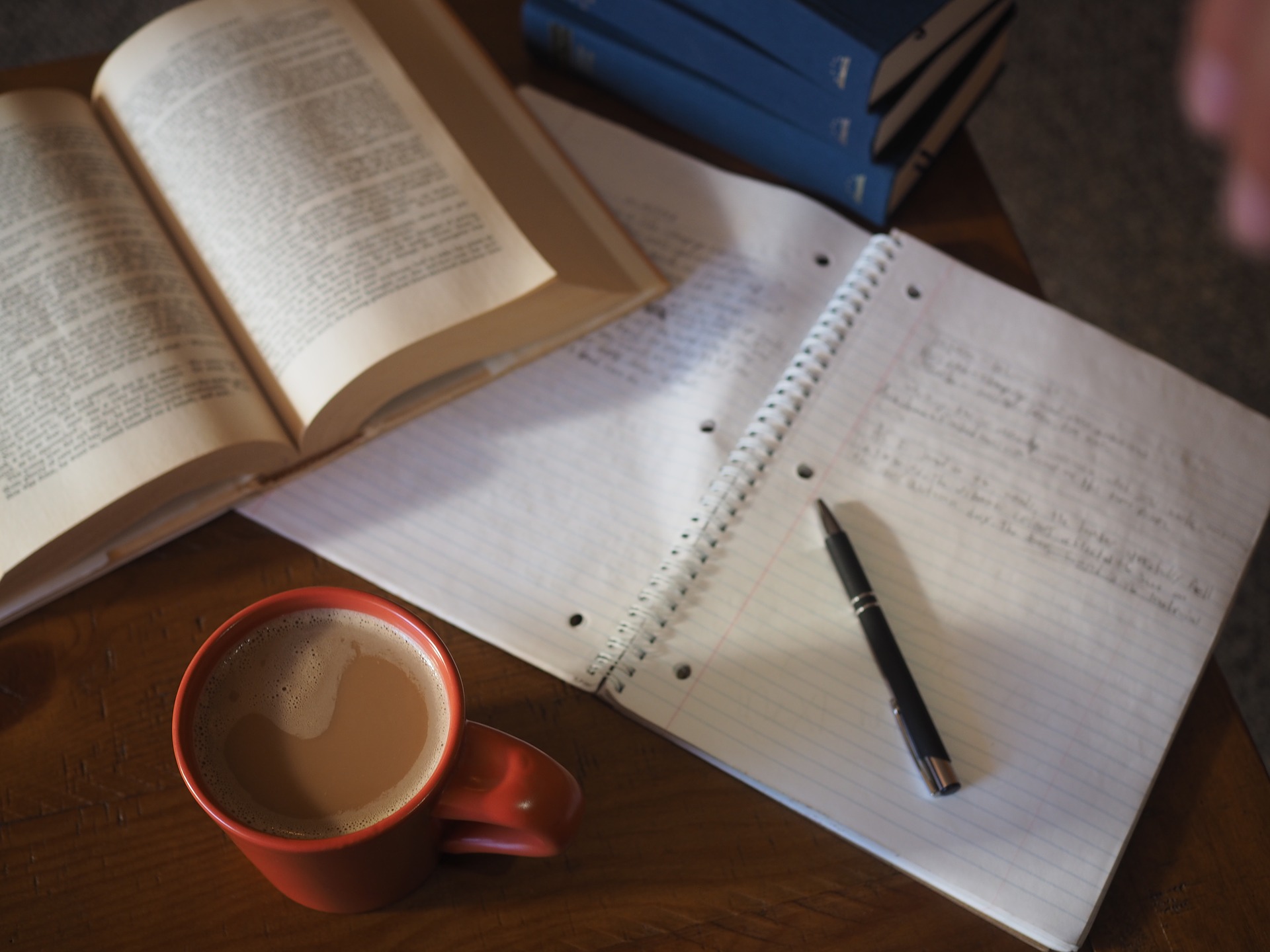 Foto de uma mesa com caderno, livro, caneta e uma caneca. Imagem ilustrativa para texto novas franquias 2021.