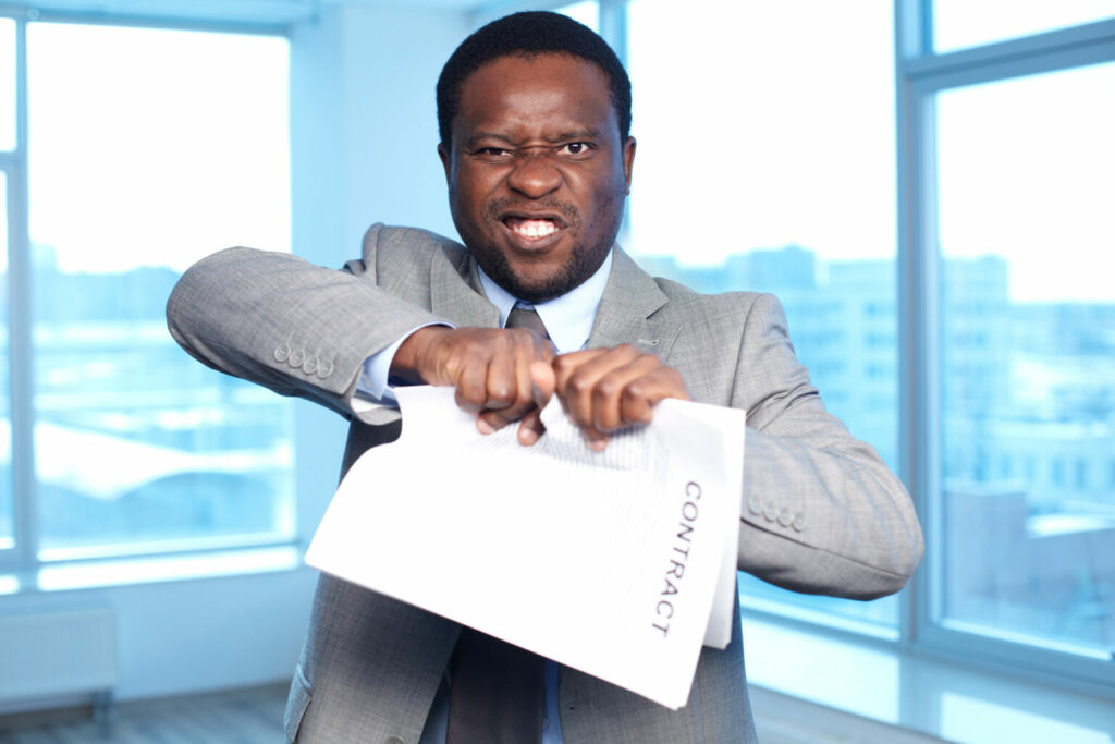 Imagem de um homem negro, com um semblante irritado, rasgando um contrato (imagem ilustrativa). Texto: repasse de unidade.