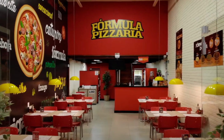 Imagem unidade Fórmula Pizzaria com logomarca e mesas para consumo pelos consumidores. Foto ilustrativa do texto franquia Fórmula Pizzaria vale a pena.