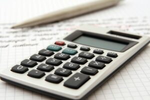 Imagem de uma calculadora em cima de um papel com números. Imagem ilustrativa de texto franquias para investir com pouco dinheiro.