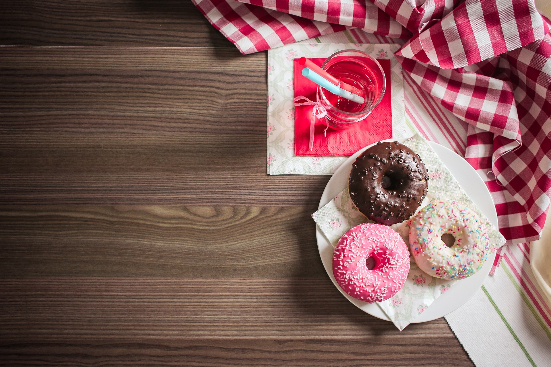 Vemos alguns donuts em uma mesa enfeitada (imagem ilustrativa).