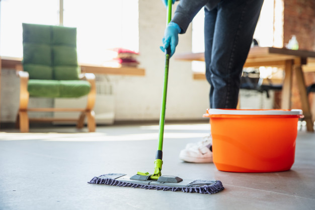 Imagem de uma pessoa limpando o chão com um esfregão. Imagem ilustrativa texto franquia de produtos de limpeza.