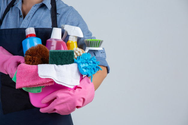 Vemos uma pessoa segurando vários produtos de limpeza (imagem ilustrativa). Texto: loja material de limpeza.