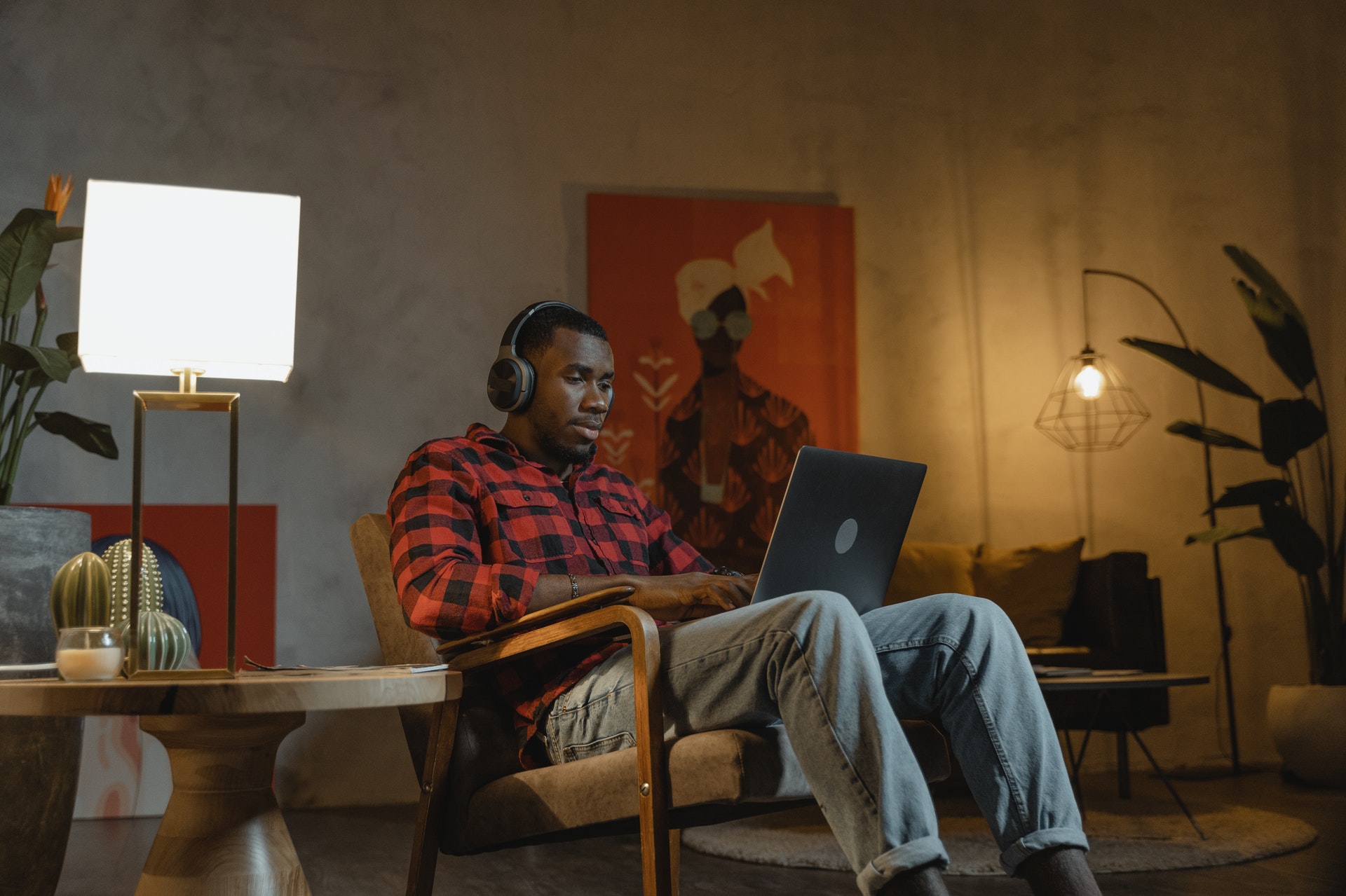 Imagem de um homem trabalhando no computador sentado no sofá de casa. Imagem ilustrativa texto empreender em casa.