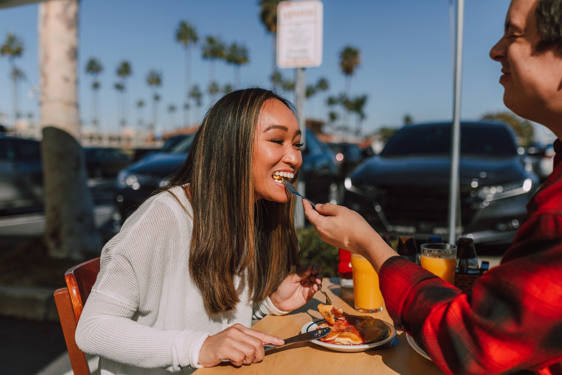 Vemos um homem dando comida na boca de uma mulher em uma espécie de encontro de casal (imagem ilustrativa). Texto: franquia açaí concept.
