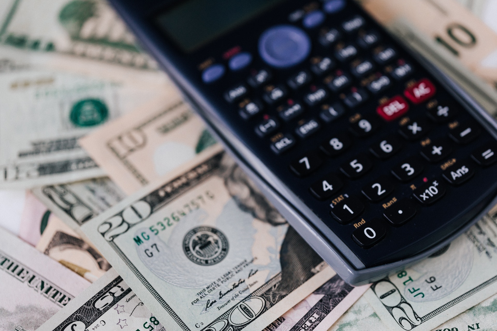 Imagem de uma calculadora e várias notas de dólares. Imagem ilustrativa texto negócio de alta lucratividade.