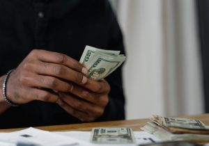 Mãos masculinas contam notas de dinheiro. Imagem ilustrativa texto como investir melhor meu dinheiro.