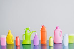 Embalagens coloridos de produtos de limpezas alinhados em superfície cinza. Ilustração do texto sobre distribuidora de produtos de limpeza para revenda.