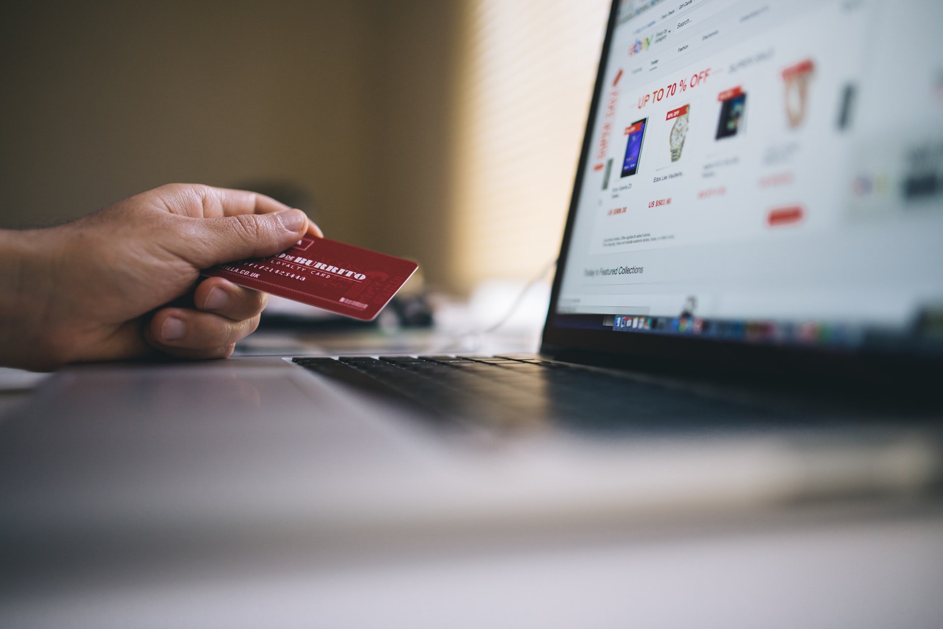Vemos que uma pessoa segura um cartão de crédito em frente a um computador; na tela, vemos um site de compras (imagem ilustrativa). Texto: ideias de pequenos negócios que deram certo.