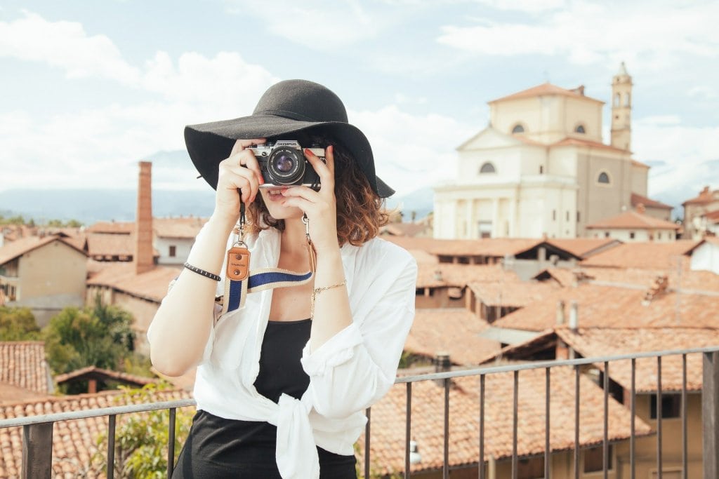 Foto de uma mulher fotografando com uma cidade atrás. Imagem ilustrativa para texto Franquia Clube Turismo.