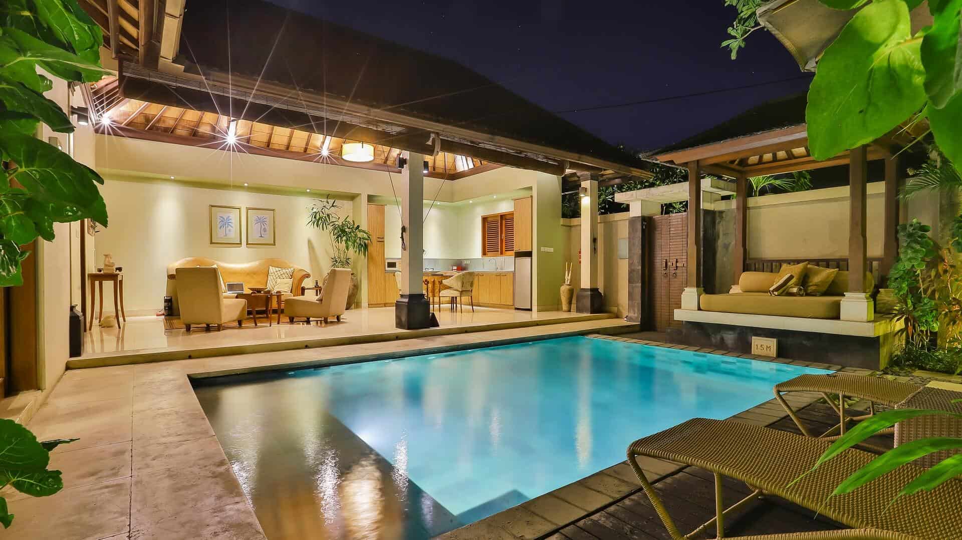 Vemos uma piscina na área externa com uma casa.