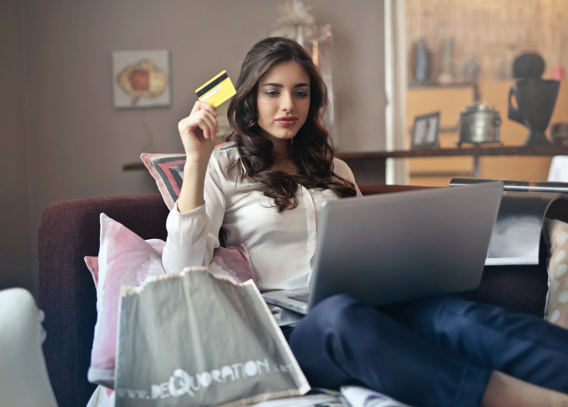 Imagem de uma mulher com um computador no colo e um cartão de crédito na mão. Imagem ilustrativa texto exclusividade territorial em franquias.