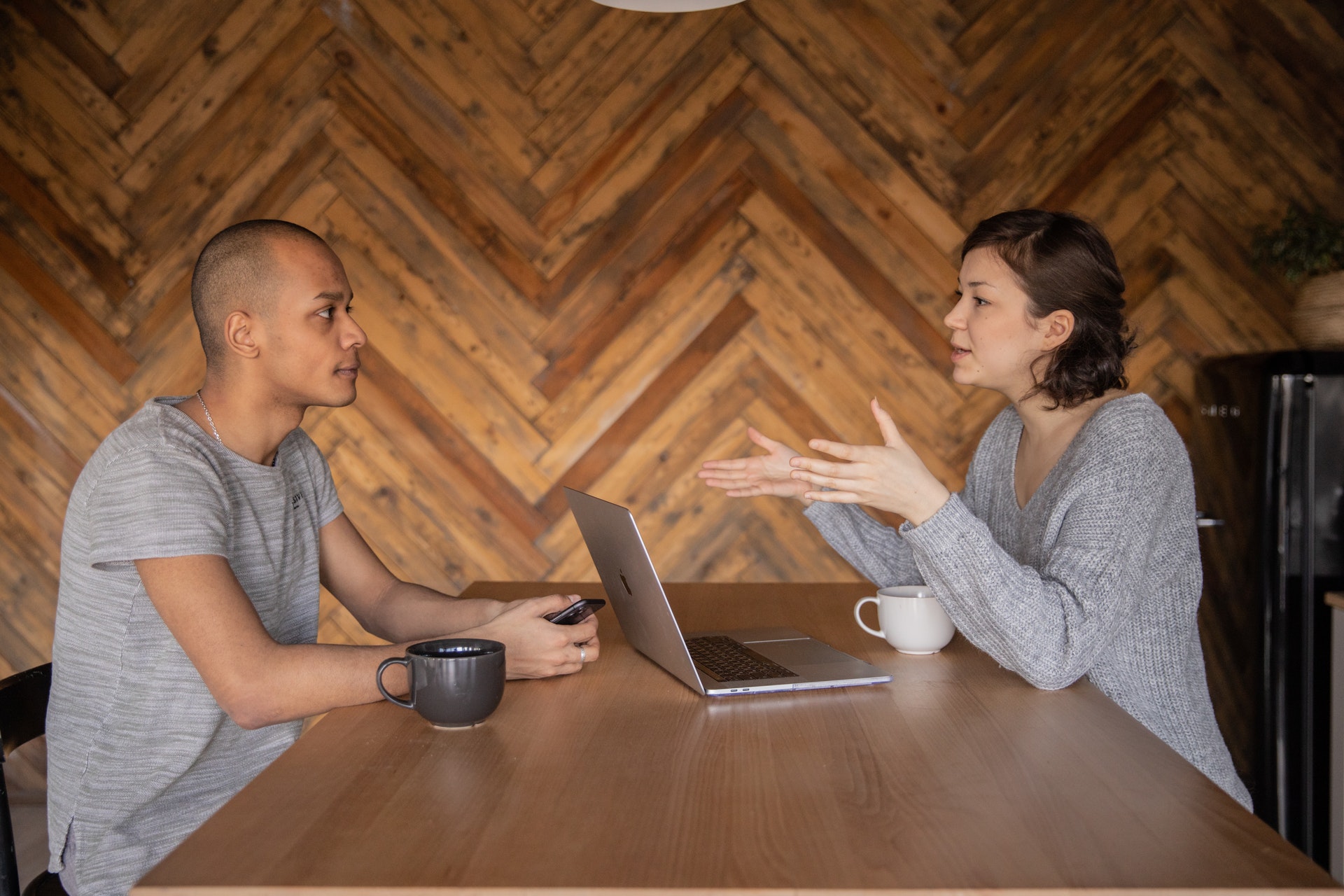Imagem de um homem e uma mulher conversando em uma mesa com um computador. Imagem ilustrativa texto franquia light.