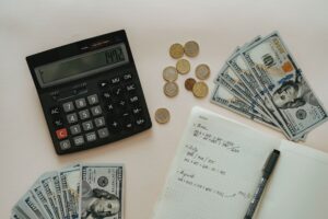 Imagem de notas de dinheiro e moderas em uma mesa, com uma calculadora e um caderno de anotações. Imagem ilustrativa texto franquias 200 mil.