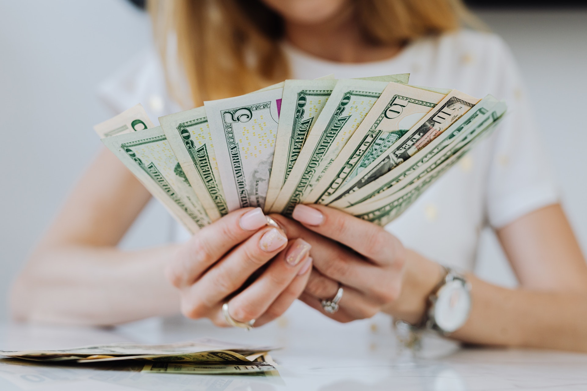 Imagem de uma mulher segurando várias notas de dólar. Imagem ilustrativa texto franquias 200 mil.