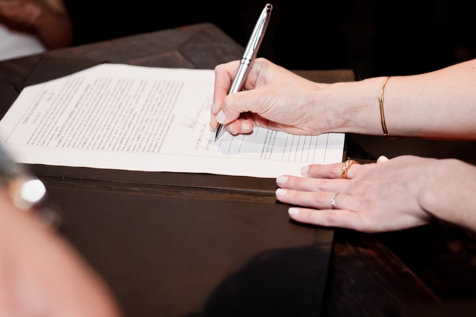 mãos de uma mulher assinando documentos ilustrativa texto como abrir uma empresa passos