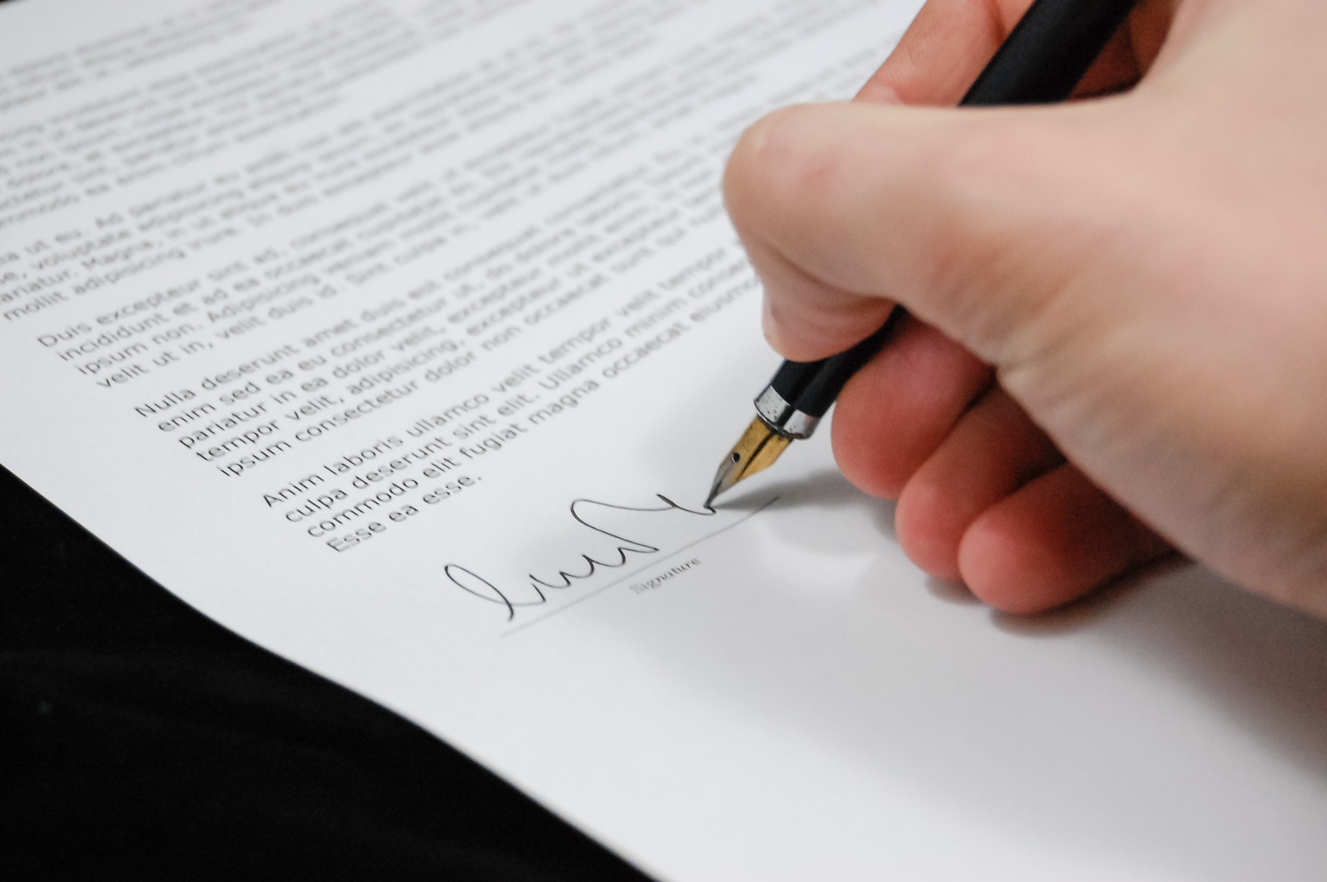 Imagem de uma mão assinando um contrato. Imagem ilustrativa texto contrato de franquia pré contrato e COF.