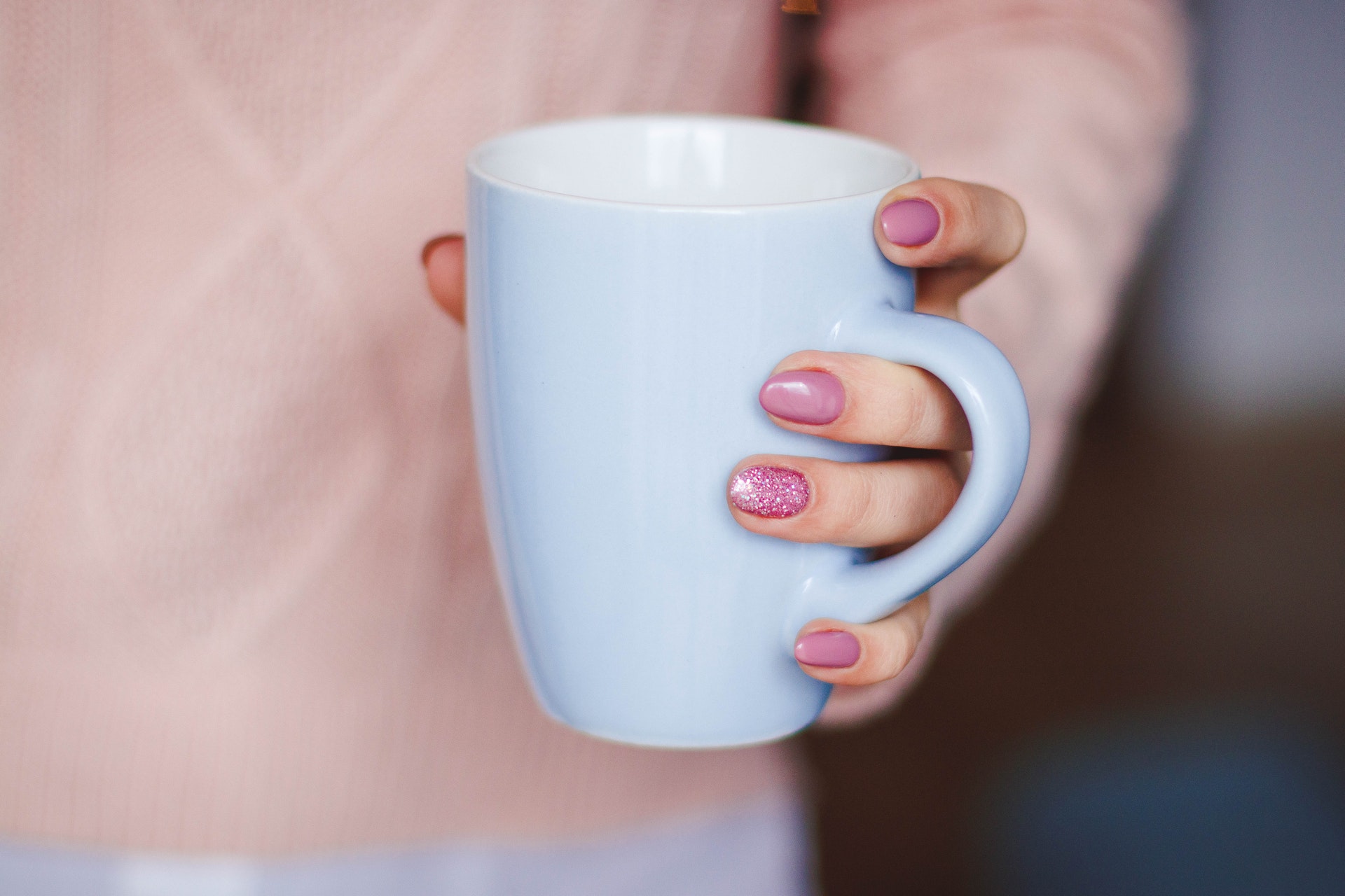 Imagem de uma mão feminina segurando uma caneca branca de chá. Imagem ilustrativa texto franquias baratas alimentação 2022.