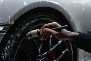 Imagem de uma pessoa limpando a roda de um carro. Imagem ilustrativa texto franquias baratas automotivas 2022.