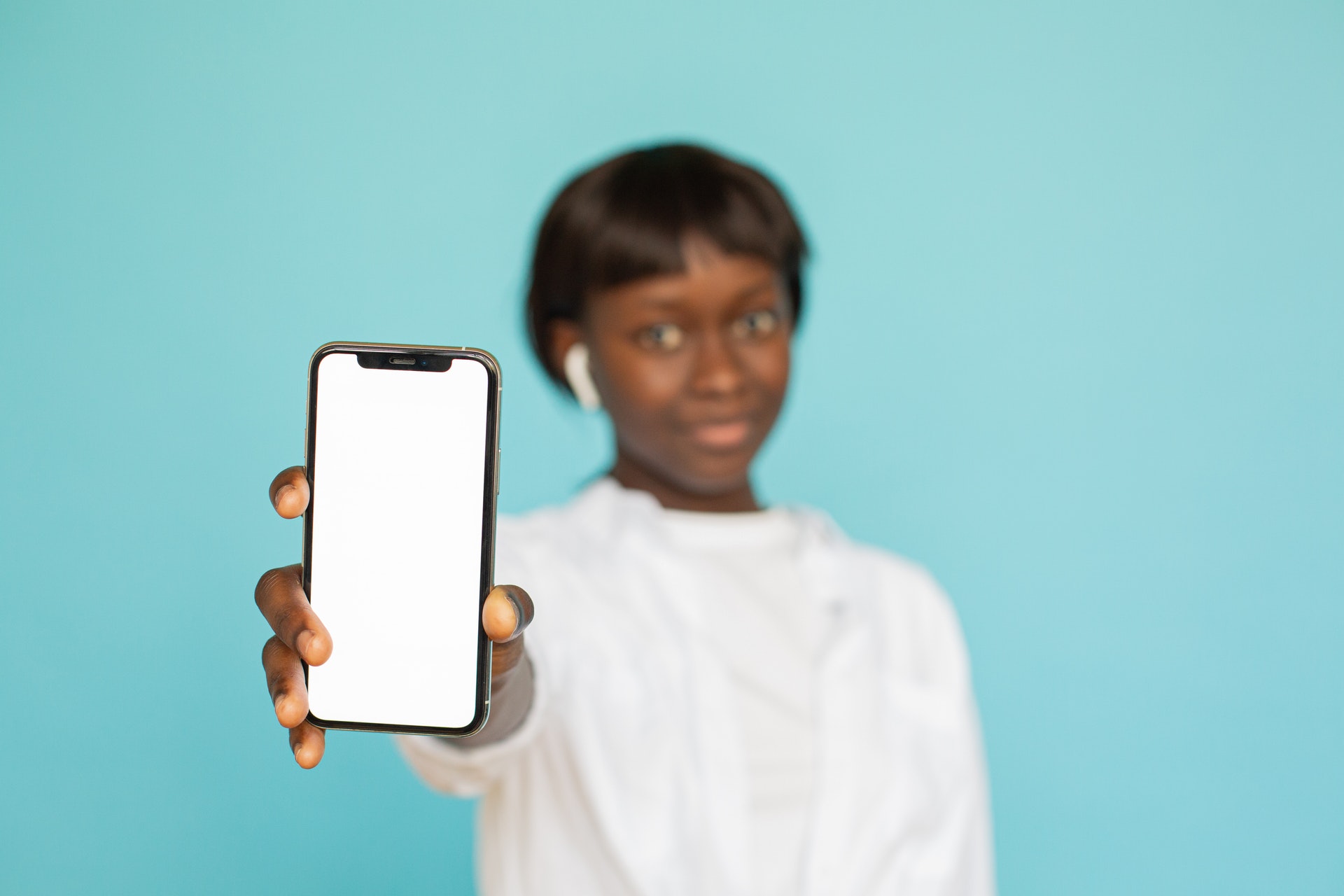 Imagem de uma mulher segurando e mostrando um celular. Imagem ilustrativa texto lucrar muito investindo pouco.