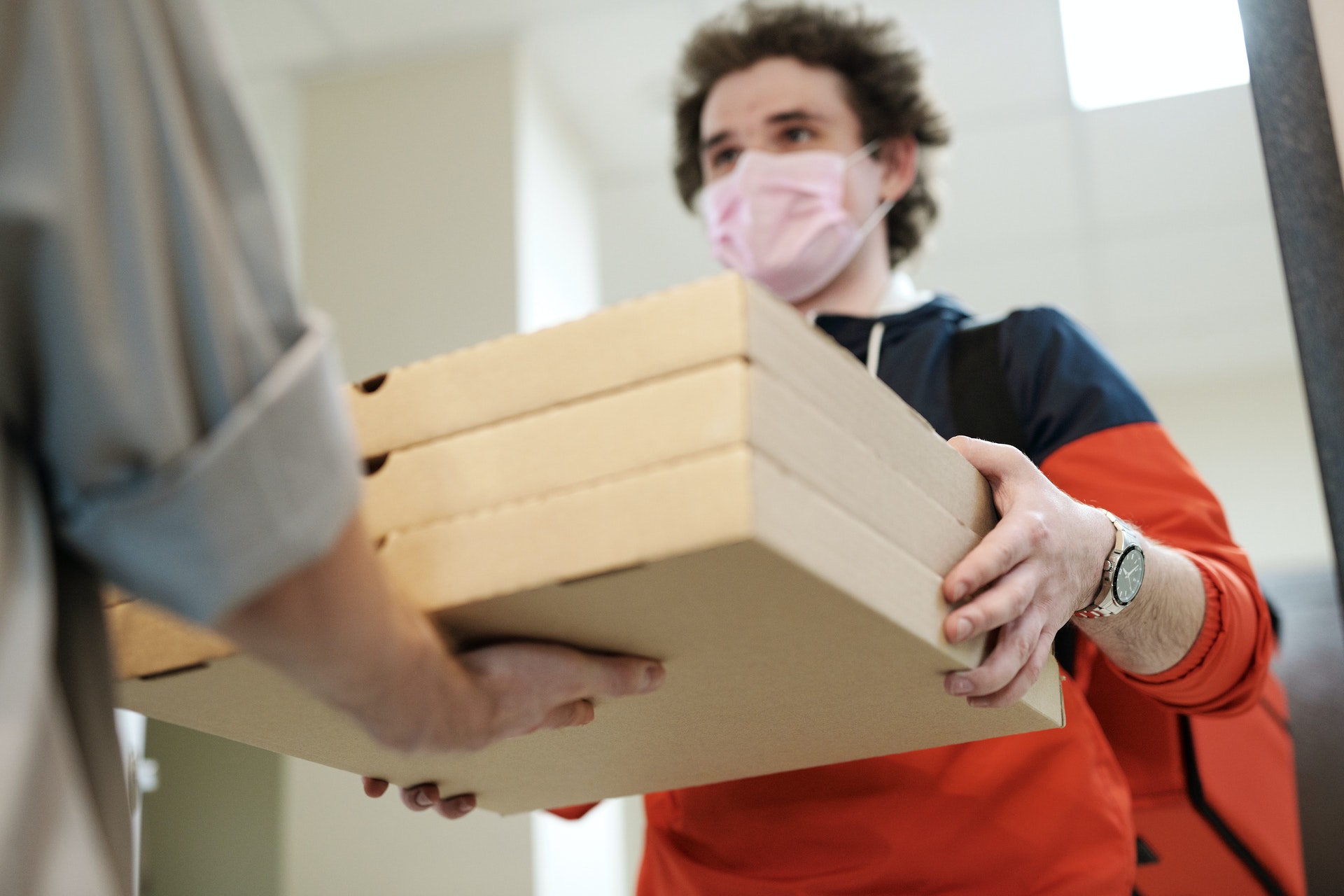 Imagem de um entregador entregando pizzas na casa de um cliente. Imagem ilustrativa texto nichos de negócios lucrativos.