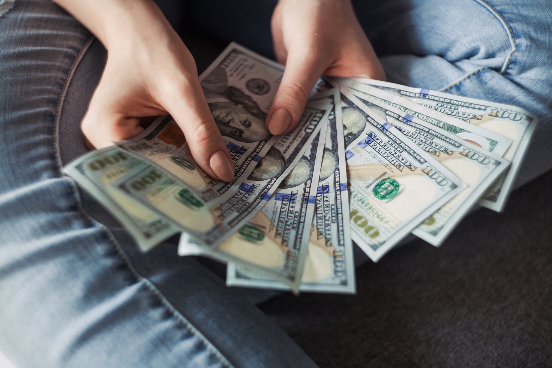 Imagem de uma pessoa segurando um grande leque de notas de dólar na mão. Imagem ilustrativa texto nichos de negócios lucrativos.