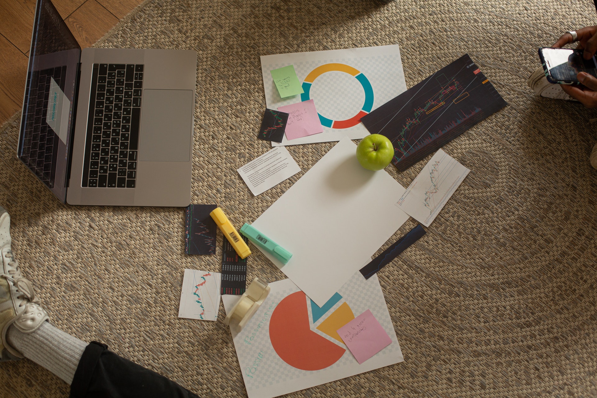 Imagem de uma mesa com um computador e papeis com gráficos desenhados. Imagem ilustrativa texto planejar o negócio próprio.