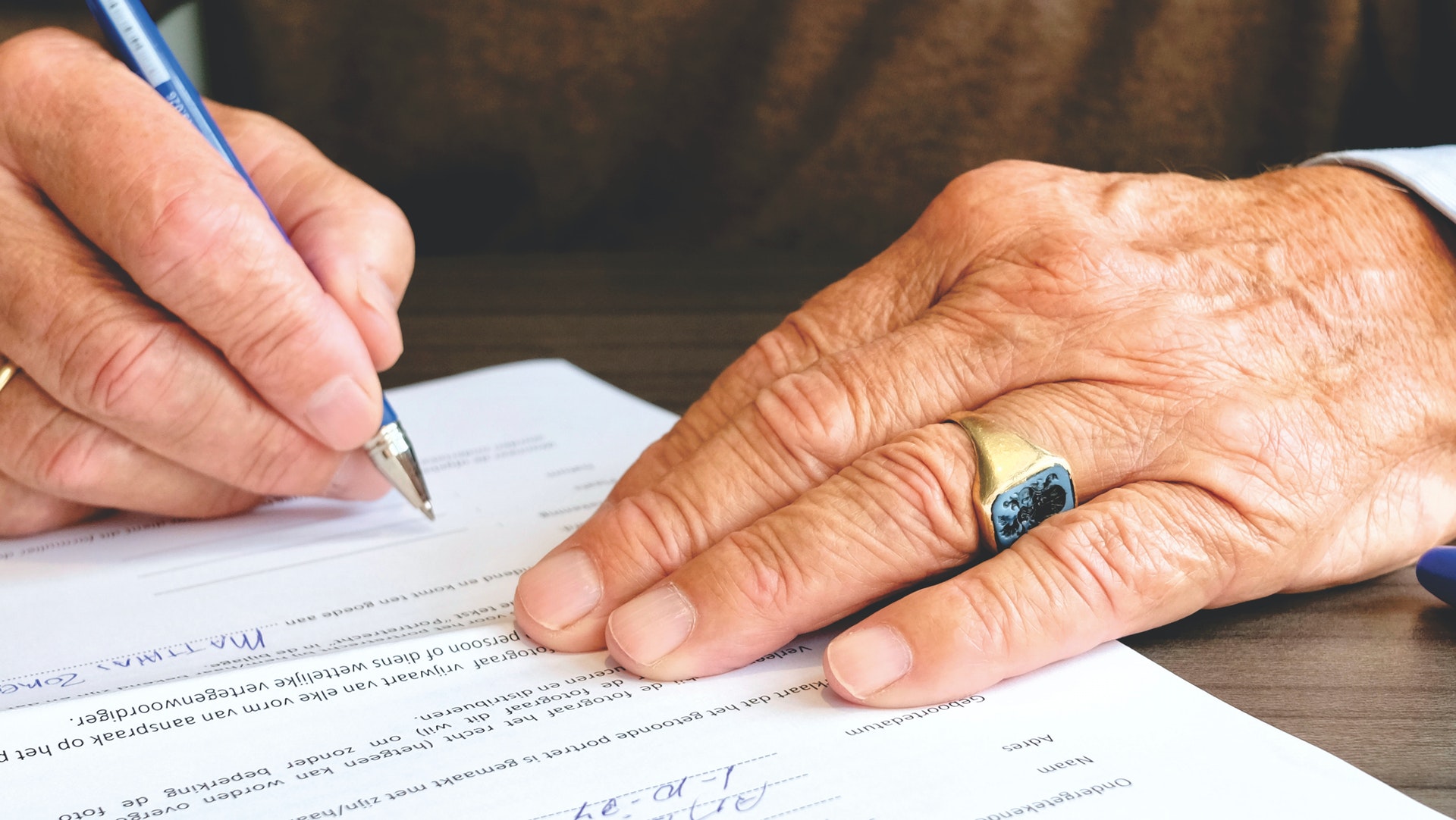 Imagem de duas mãos sobre um documento assinando o papel. Imagem ilustrativa texto cláusula arbitral em contrato de franquias.