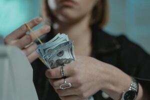 Imagem de uma mulher segurando várias notas de dinheiro. Imagem ilustrativa texto franquias com pouco investimento.