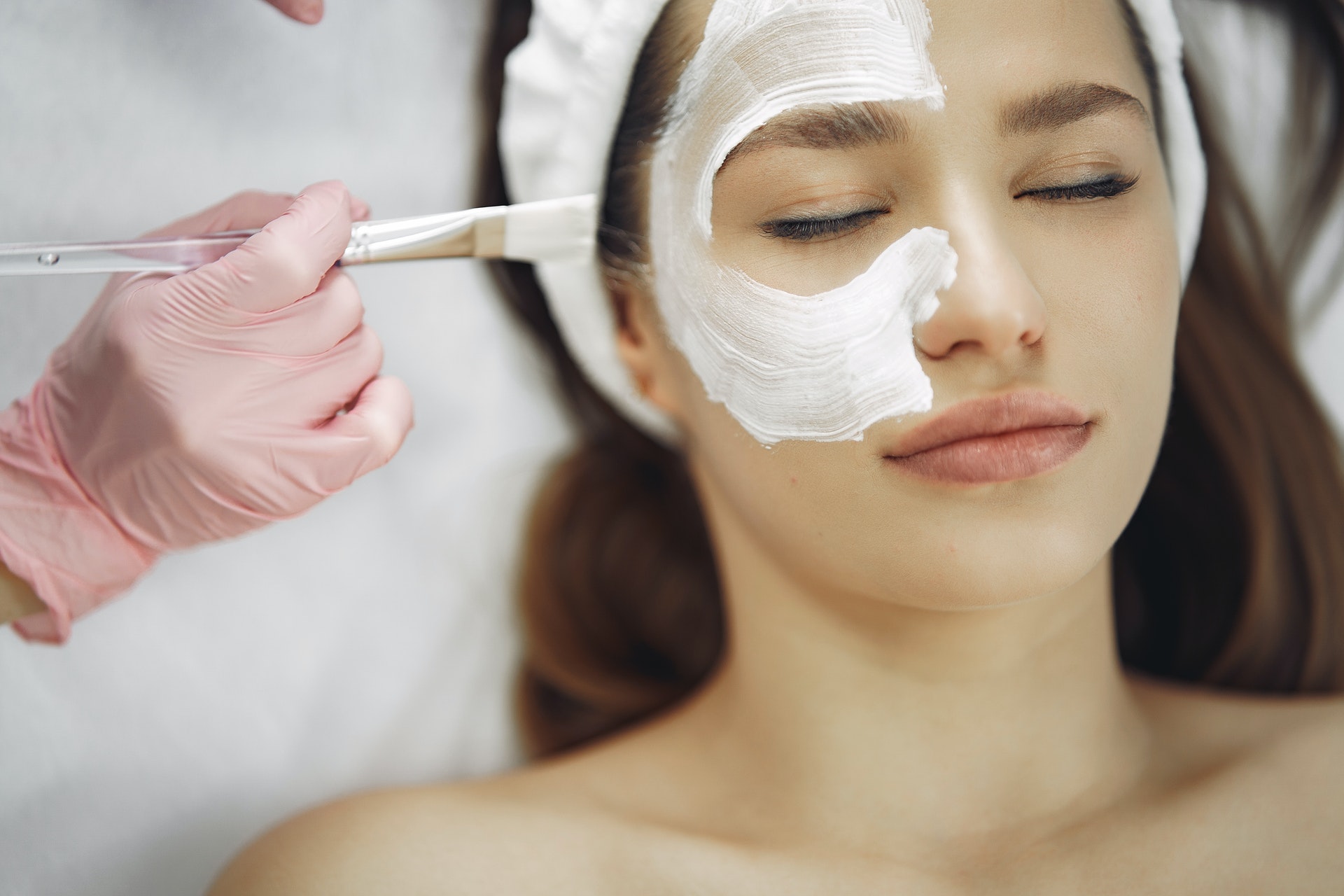 Imagem de uma mulher recebendo um tratamento estético com um creme branco no rosto. Imagem ilustrativa texto franquias para investir sem medo.